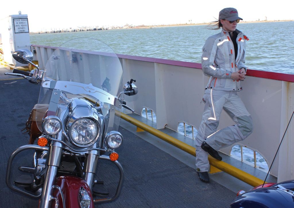 Women Who Ride Motorcycles: On the Galveston Ferry at the end of a three day journey on Indian motorcycles. The image shows Cristi on the deck of a ship looking out at the water, with an Indian motorcycle next to her. (Photo by Robert Pandya.)
